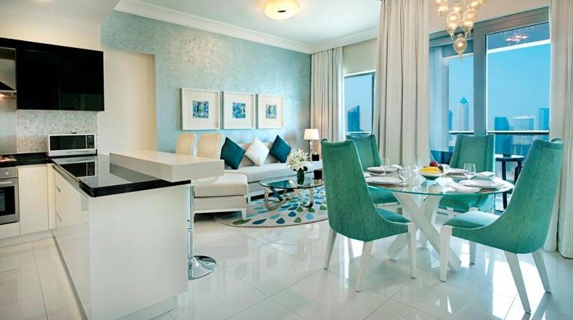 a kitchen and dining room with a table and green chairs at HotelApart Dubai Mall st with Full Burj Khalifa View in Dubai