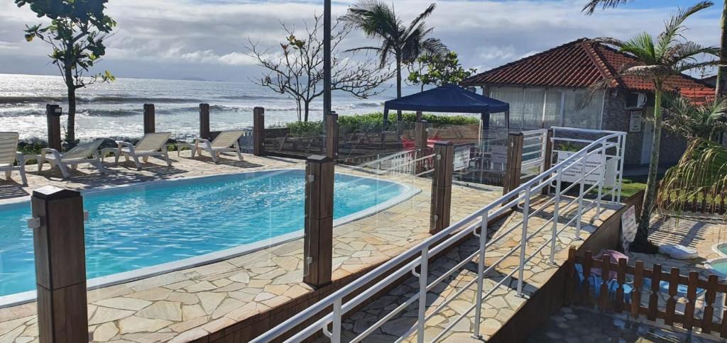 a swimming pool with the ocean in the background at Hotel Nils in Itapoa
