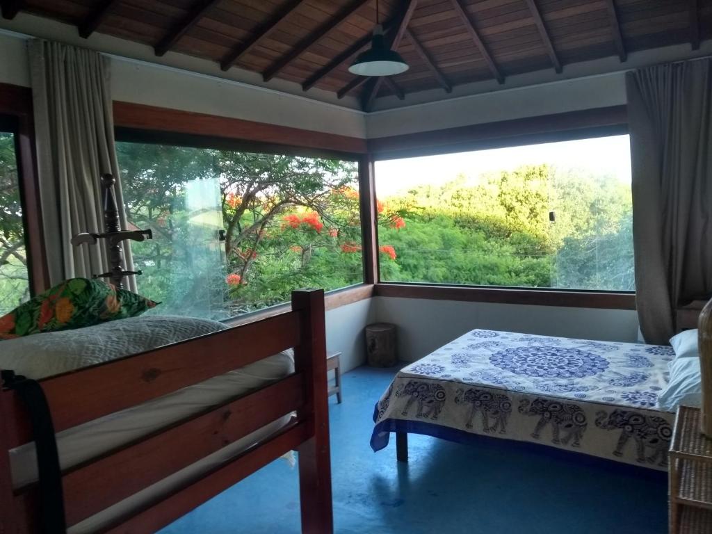 um quarto com uma cama e uma grande janela em Pousada Recanto Devas em Cabo Frio