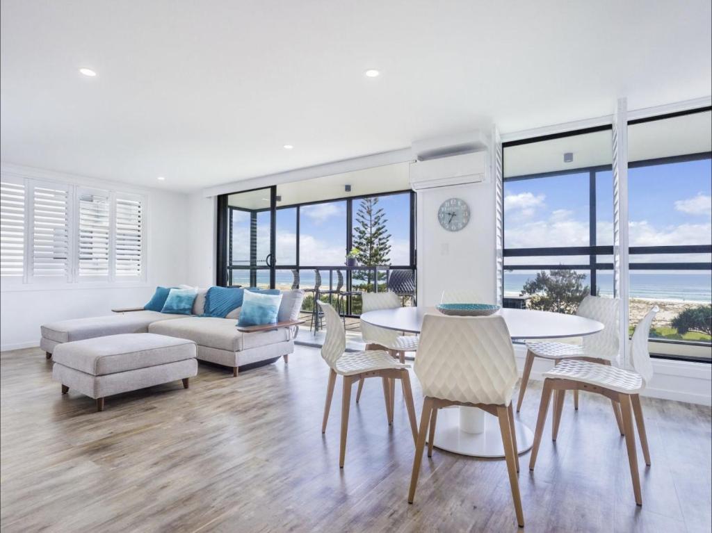 Una sala de estar con un sofá, una mesa y sillas. en Kirra Waves, en Gold Coast