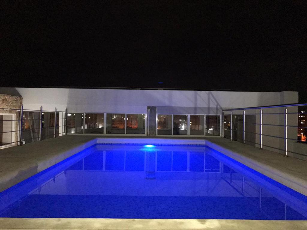una gran piscina por la noche con luces azules en Aparta Suites La Flora, en Cali