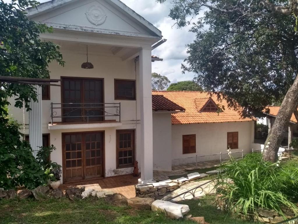 a white house with a tree in front of it at Casa Temporada Vila Residencial Furnas, Capitólio MG in Furnas