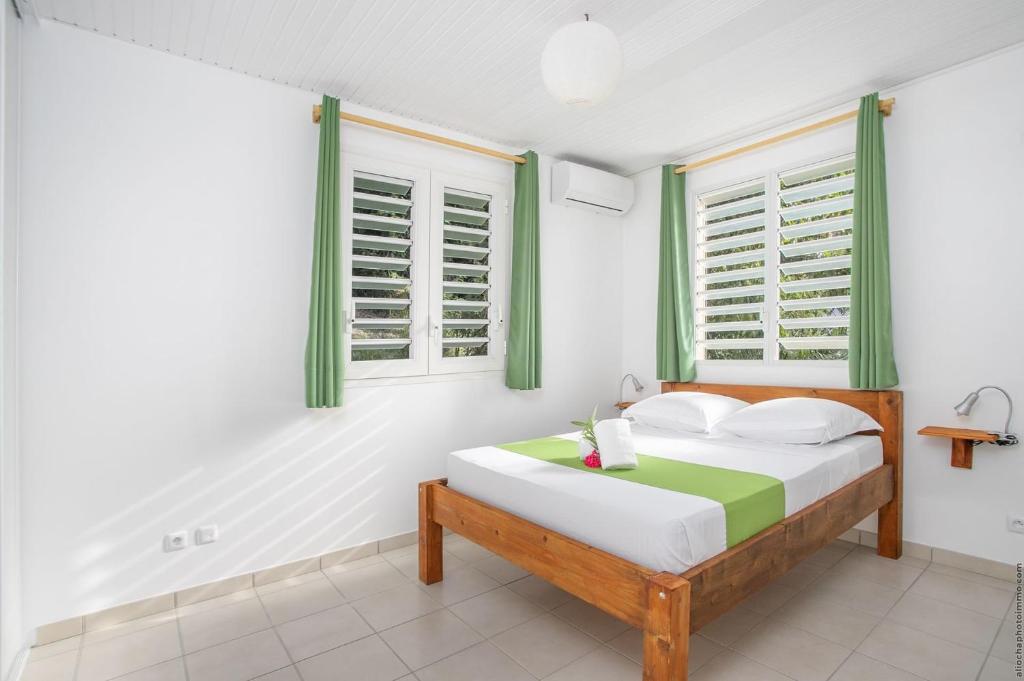 a bedroom with a bed with green shuttered windows at SCI DRELA in La Trinité