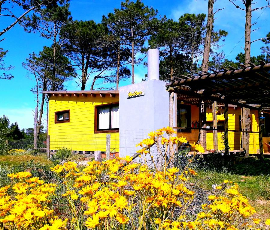 a yellow house with yellow flowers in the foreground at DiaBro's in Punta Del Diablo