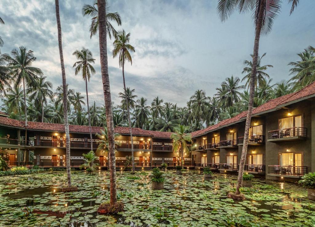 uma vista para o resort a partir da água com palmeiras em RVR Sarovar Portico em Rāzole