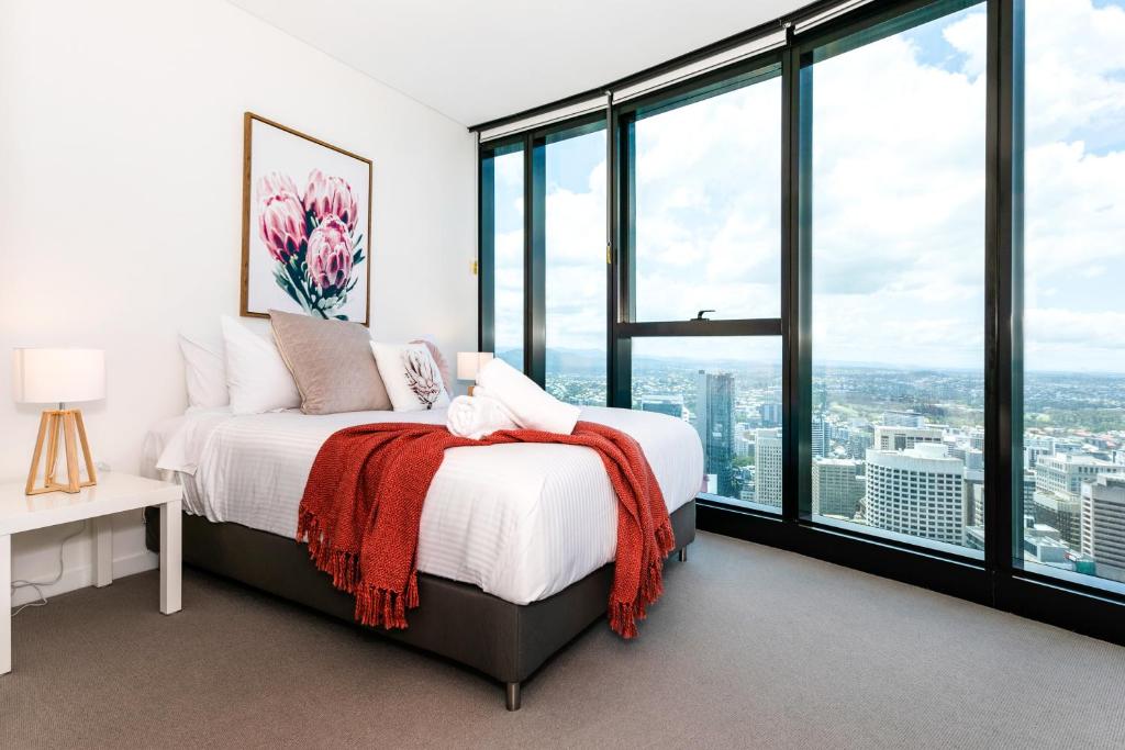 a bedroom with a bed and large windows at Lvl 59 Skytower Amazing Views CBD Wifi Carpark by Stylish Stays in Brisbane