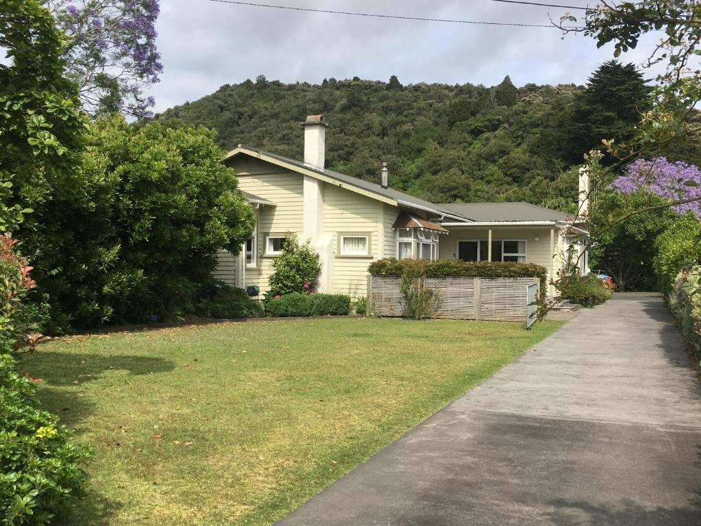 a white house with a hill in the background at School Lane Guesthouse in Whangarei