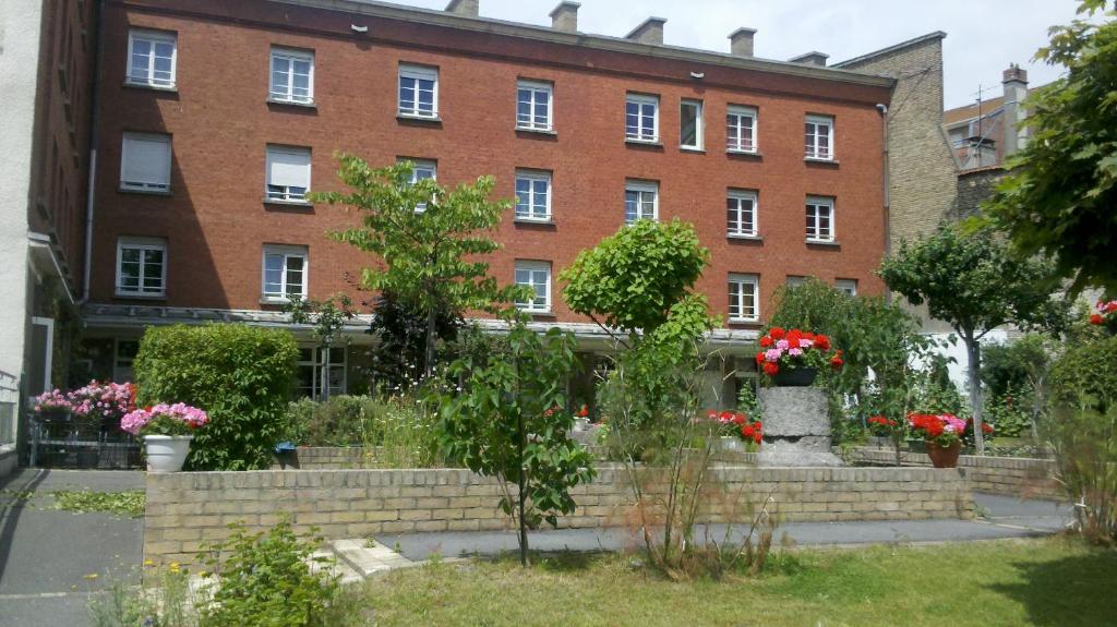 a large brick building with flowers in front of it at Hôtel Les Jardins Dunkerque centre in Dunkerque