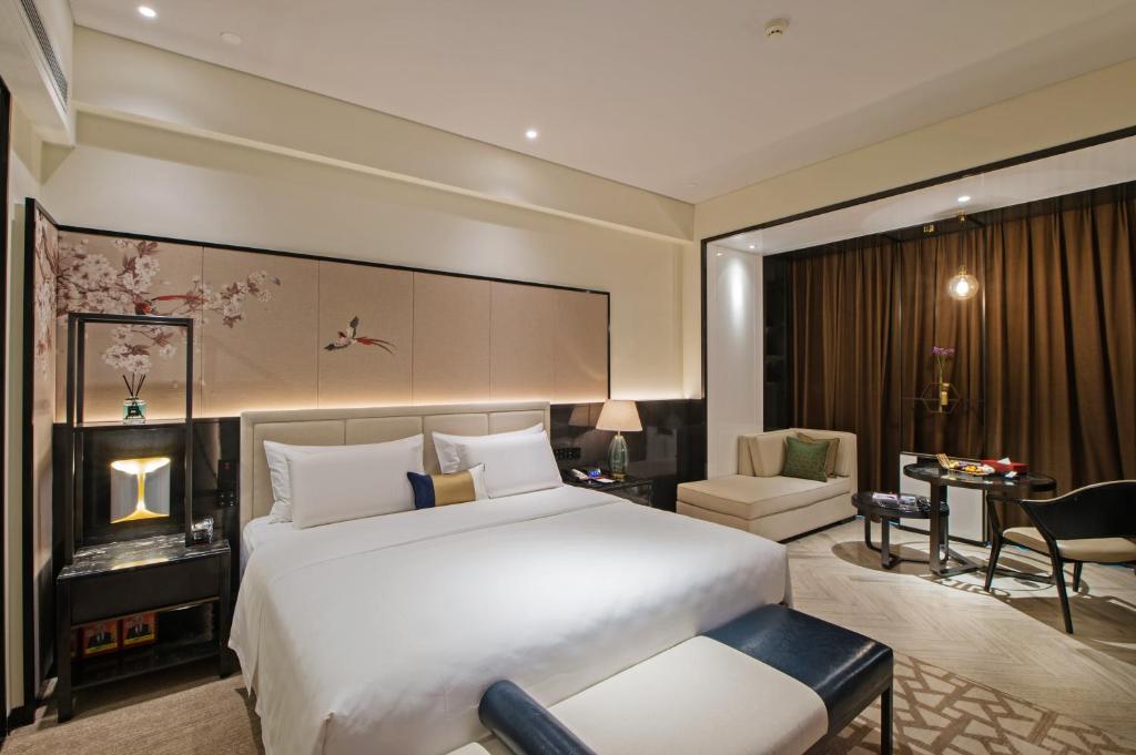 1 dormitorio con 1 cama blanca grande y escritorio en Rainbird Hotel, en Chengdú