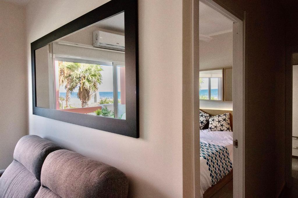 a living room with a mirror and a couch at Apartasuites Royal Zahara, Máximo confort con vistas al mar in Zahara de los Atunes