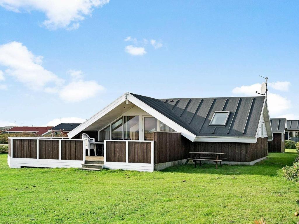 a house with a black roof on a green field at 8 person holiday home in Harbo re in Harboør