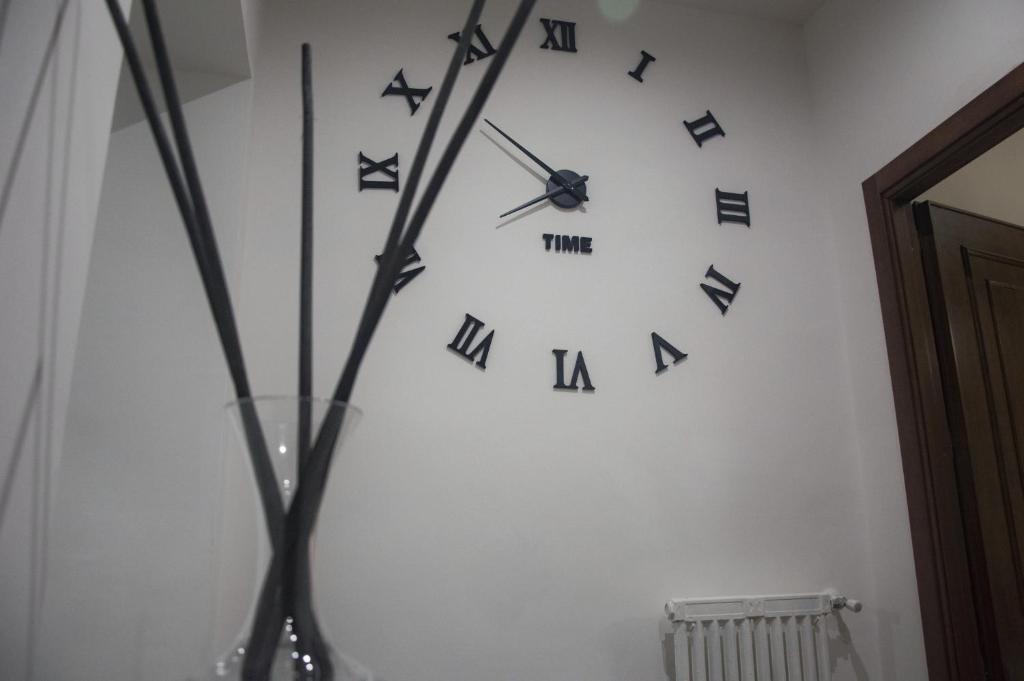 Un orologio su un muro bianco con delle lettere nere sopra. di TIME a Roma