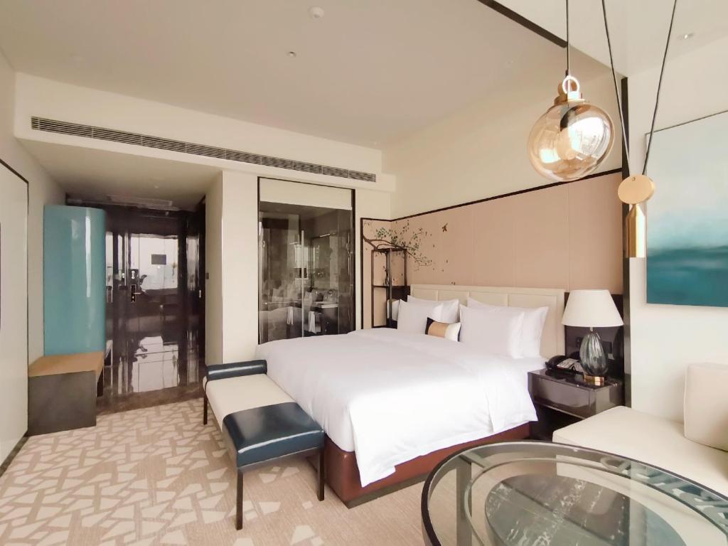 a bedroom with a bed and a glass table at Rainbird Hotel in Chengdu