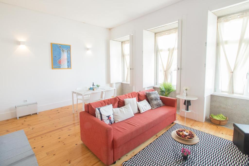 a living room with a red couch and some windows at Smooth Oporto Apartment by Porto City Hosts in Porto