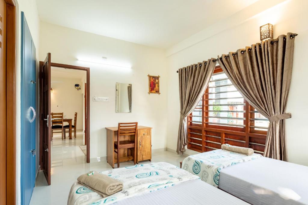 a bedroom with two beds and a table and a window at Poetrie Homestay in Ernakulam