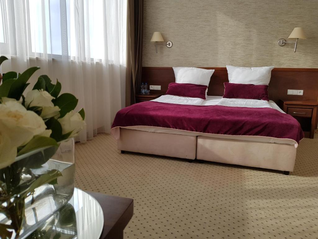 Un dormitorio con una cama con sábanas y almohadas púrpuras. en Hotel Starzyński, en Płock