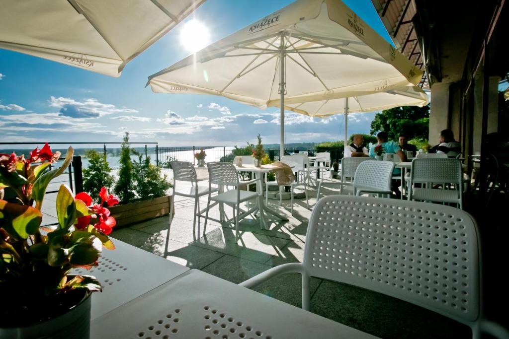 Un patio con sillas y mesas blancas y sombrillas. en Hotel Starzyński, en Płock