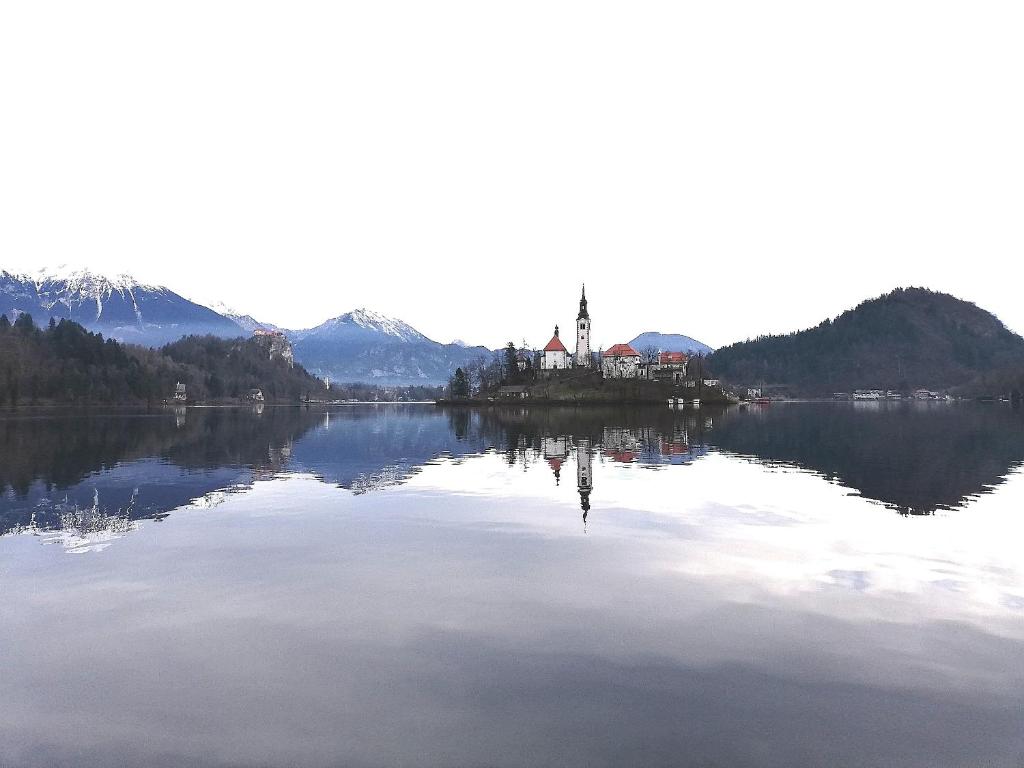 un reflejo de una iglesia en un lago con montañas en Apartmaji Alenka, en Bled