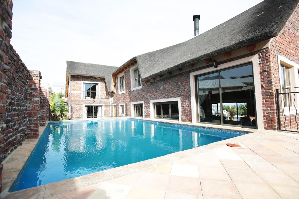 a swimming pool in front of a brick building at 19th Hole Golf Villa Guesthouse in Worcester