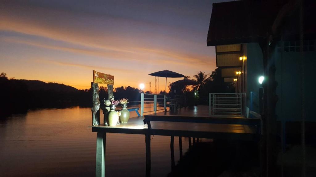 a dock with a table with flowers and an umbrella at Khum Thong Resort in Takua Pa