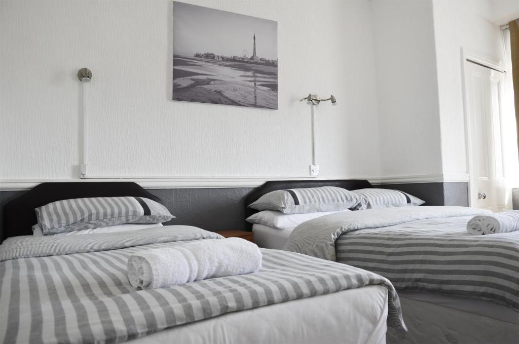 3 Betten in einem Zimmer mit einem Bild an der Wand in der Unterkunft The Gurkha Hotel in Blackpool