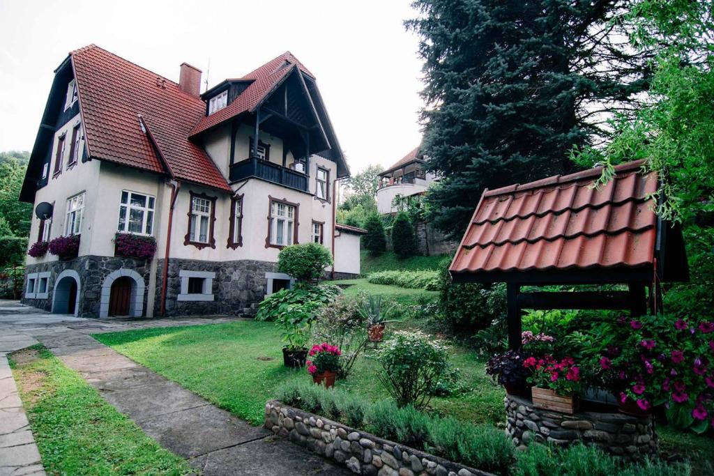 a house with a red roof and a yard with flowers at Staszica16 in Złoty Stok