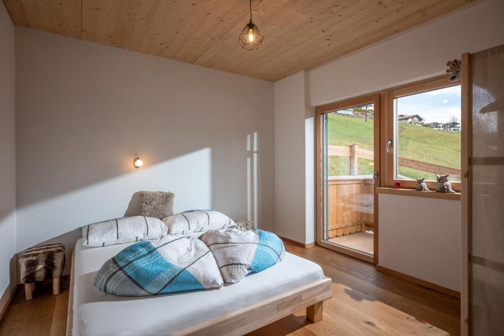 una camera da letto con letto, cuscini e finestra di Alpenchalet "DAHOAM" a Going