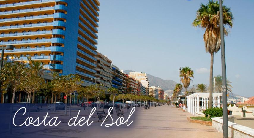 een straat in een stad met palmbomen en gebouwen bij apartamento con vista al mar in Benalmádena