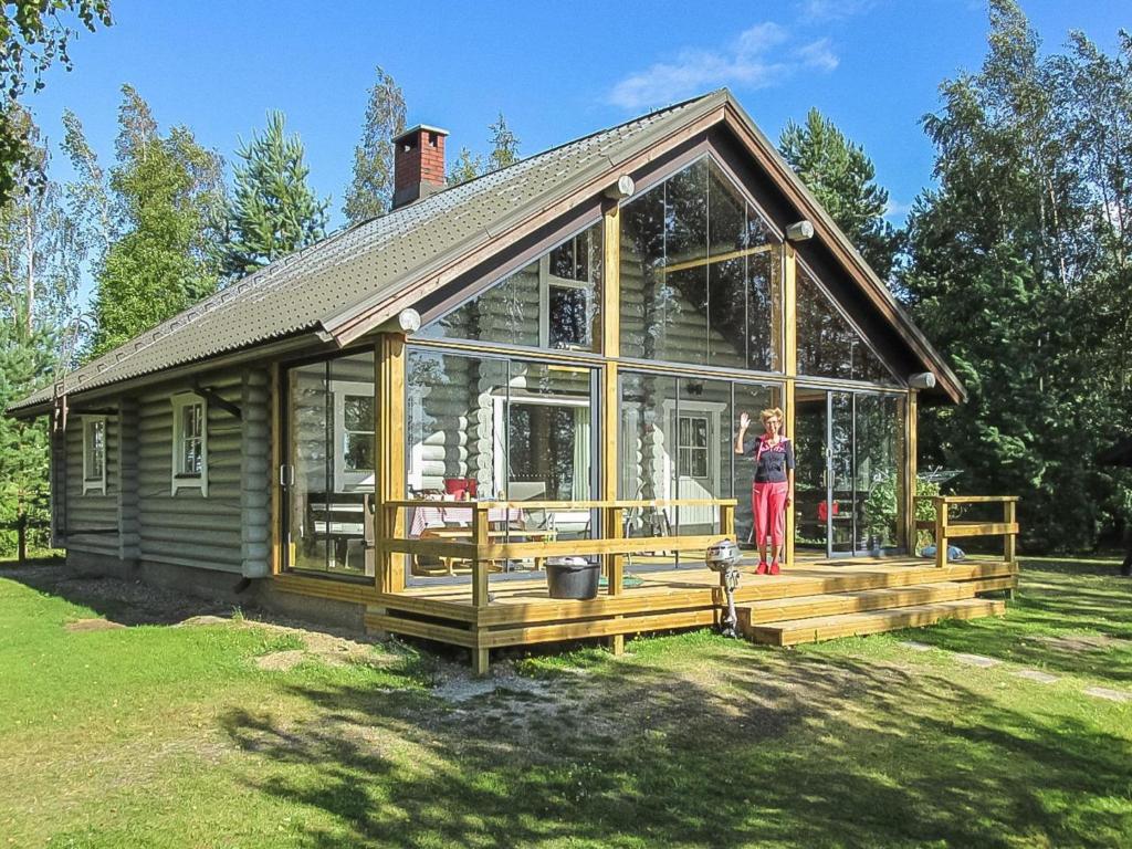a woman standing on the deck of a house at Holiday Home Tuulikannel by Interhome in Hillilä