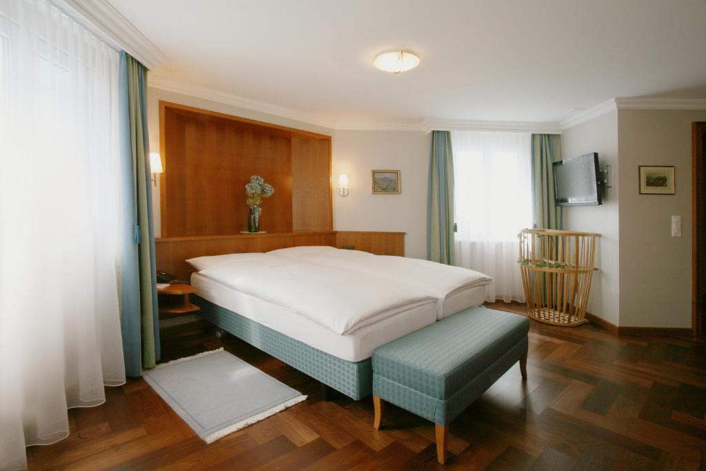 アッペンツェルにあるホテル ヘヒト アッペンツェルのベッドルーム(大きな白いベッド1台、ベンチ付)