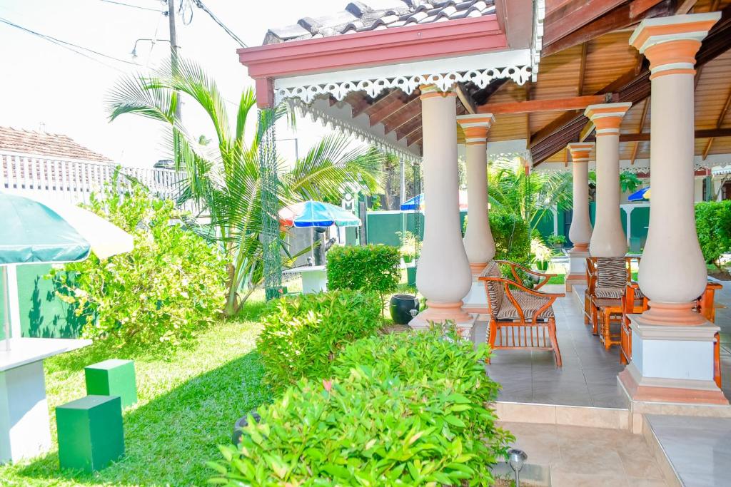 a patio of a house with chairs and umbrellas at The Brtish Independence Inn in Negombo