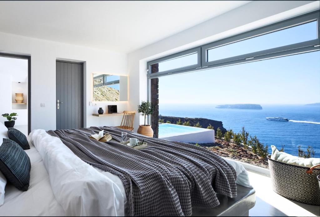 a bedroom with a large bed with a view of the ocean at Coco-Mat Hotel Santorini in Akrotiri