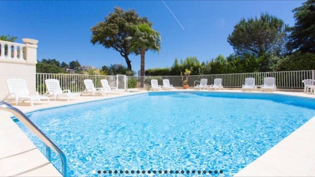 une grande piscine avec des chaises et un arbre dans l'établissement Cozy studio with sea view, swimming pool and greenery, à Cannes