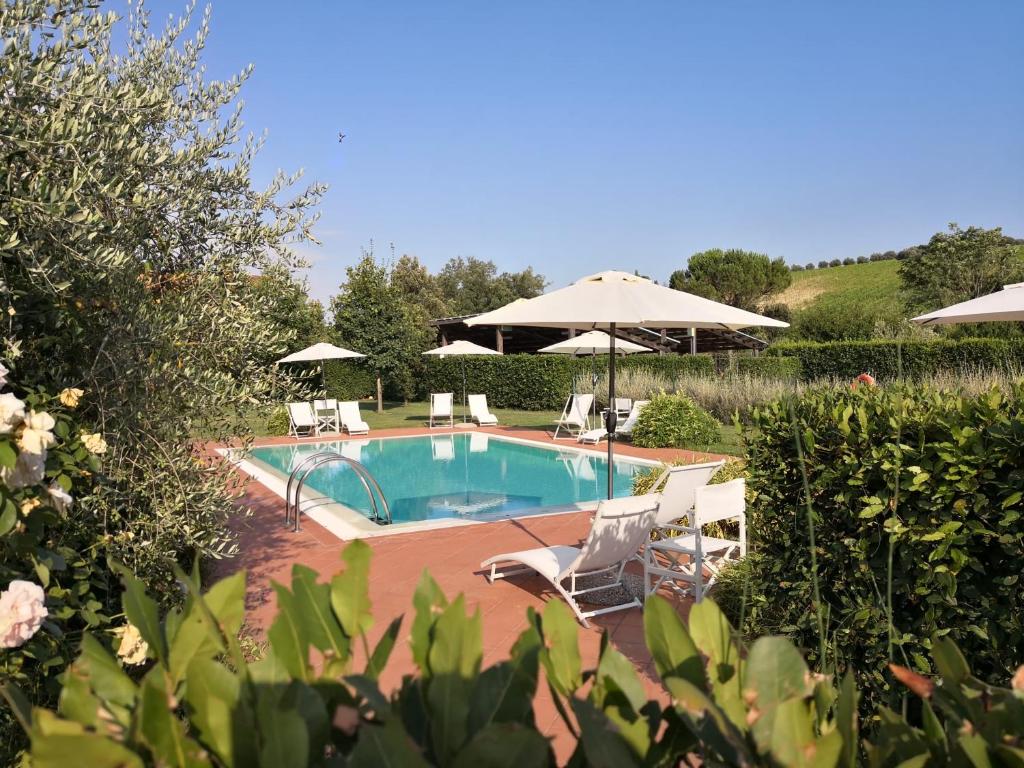 einen Pool mit Stühlen und einem Sonnenschirm in der Unterkunft Borgo Piccaratico in Vinci