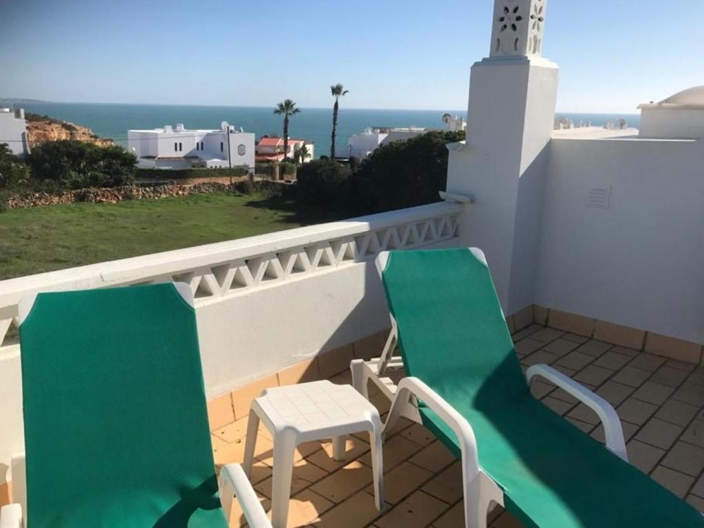 a balcony with two green chairs and a lighthouse at Seaview Terrace Benagil Villa 45 in Benagil