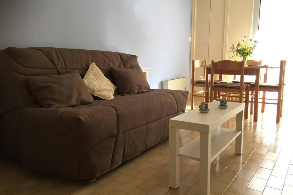 een woonkamer met een bruine bank en een tafel bij Les Lavandières in Vernet-les-Bains