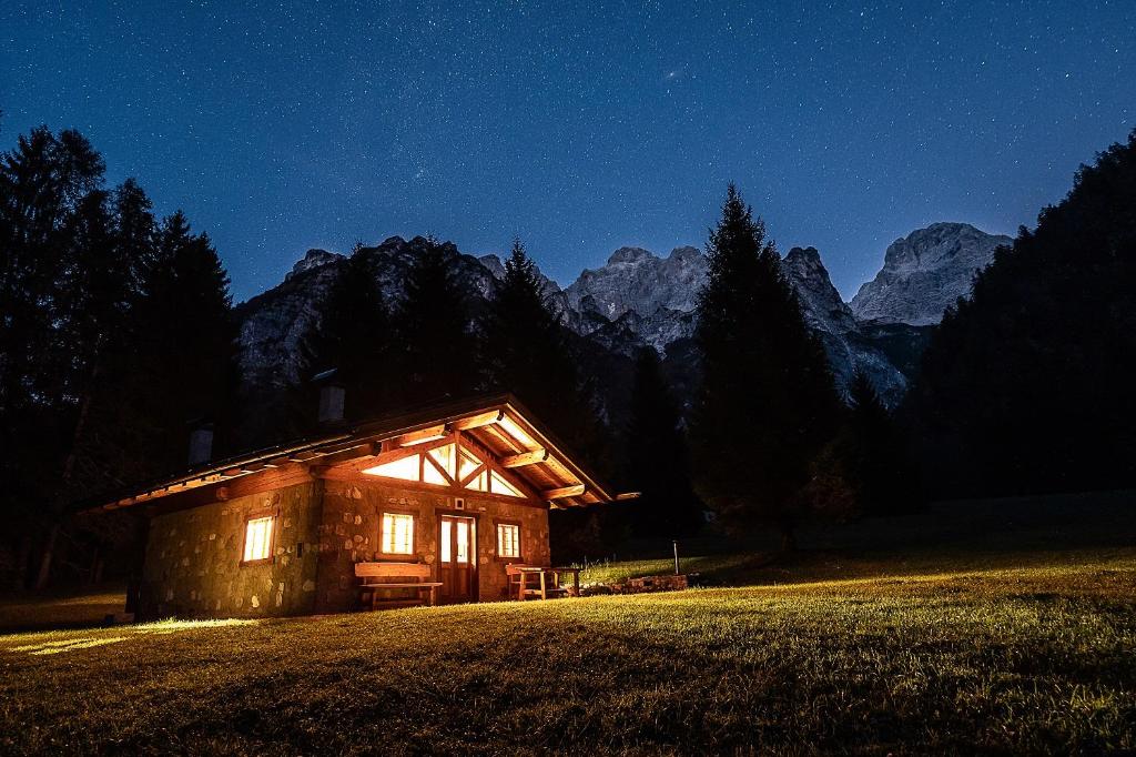 a log cabin in the middle of a field at night at Baita Valon - Alpine Hideaway in Comano Terme