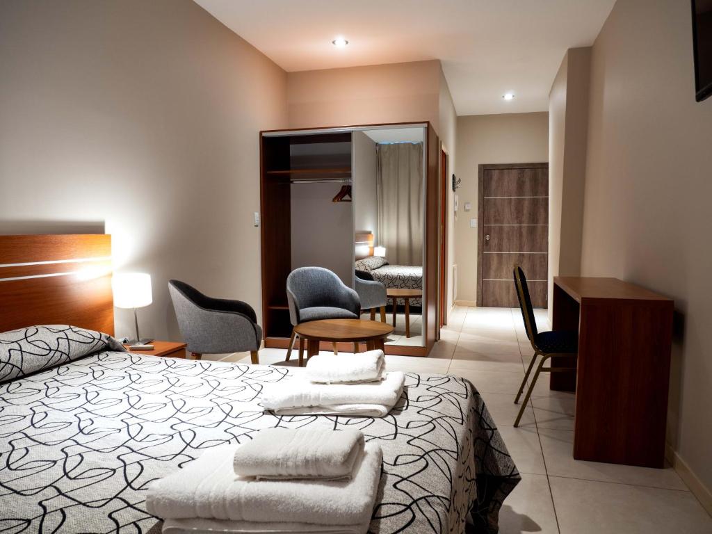 a bedroom with a bed and a desk and chairs at LELOIR Suites & Meetings in Neuquén