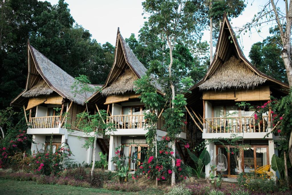 a large house with a thatched roof at Fox & The Firefly Cottages in Loboc