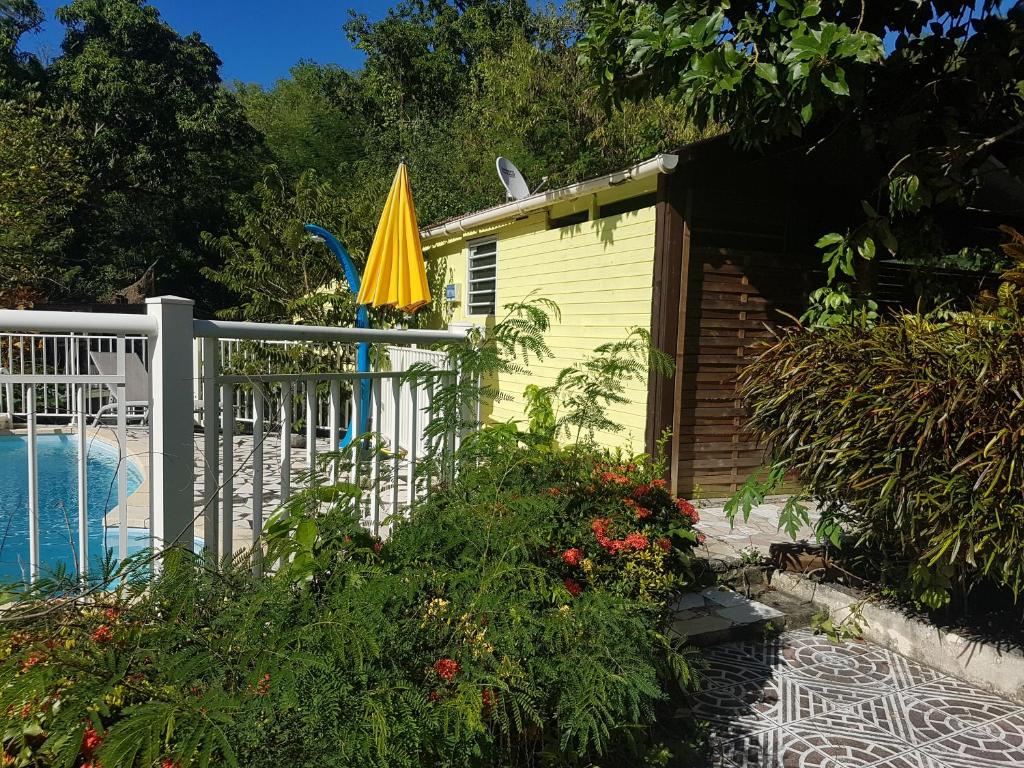 une maison jaune avec un parasol à côté d'une piscine dans l'établissement Ti kaz a Annick, à Bouillante
