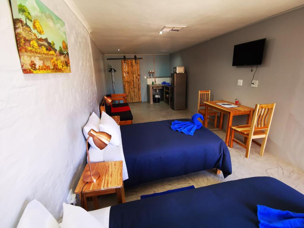 a hotel room with two beds and a table and a television at Swartberg Cottages in Prince Albert