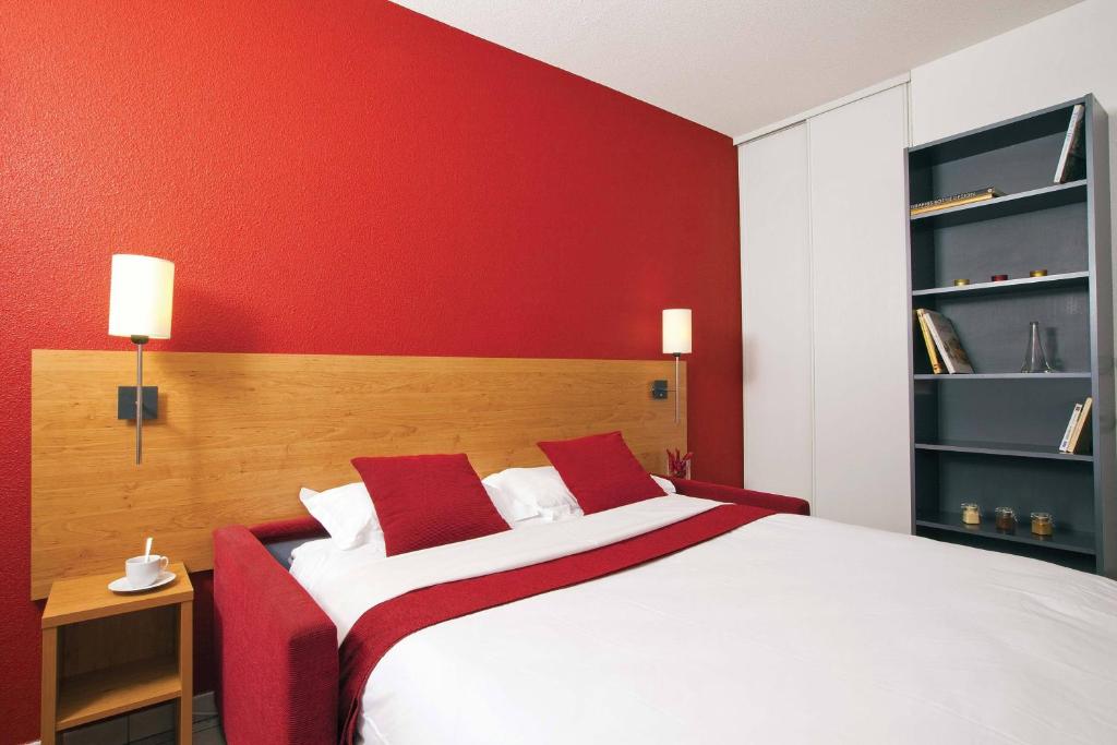 Séjours & Affaires Lyon Park Lane في ليون: غرفة نوم حمراء مع سرير أبيض بجدران حمراء