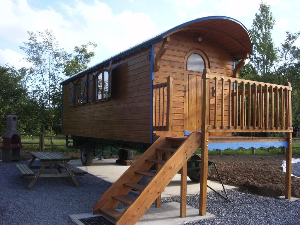 a wooden play house with a slide and a bench at Roulottes des Trolls in La Boussac