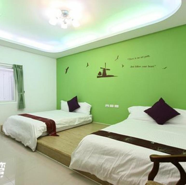 two beds in a room with green walls at Nandian Homestay in Eluan
