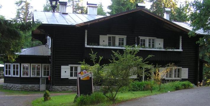 ein schwarzes Haus mit weißen Fenstern und einem Schild davor in der Unterkunft Chata Tokáň in Jetřichovice