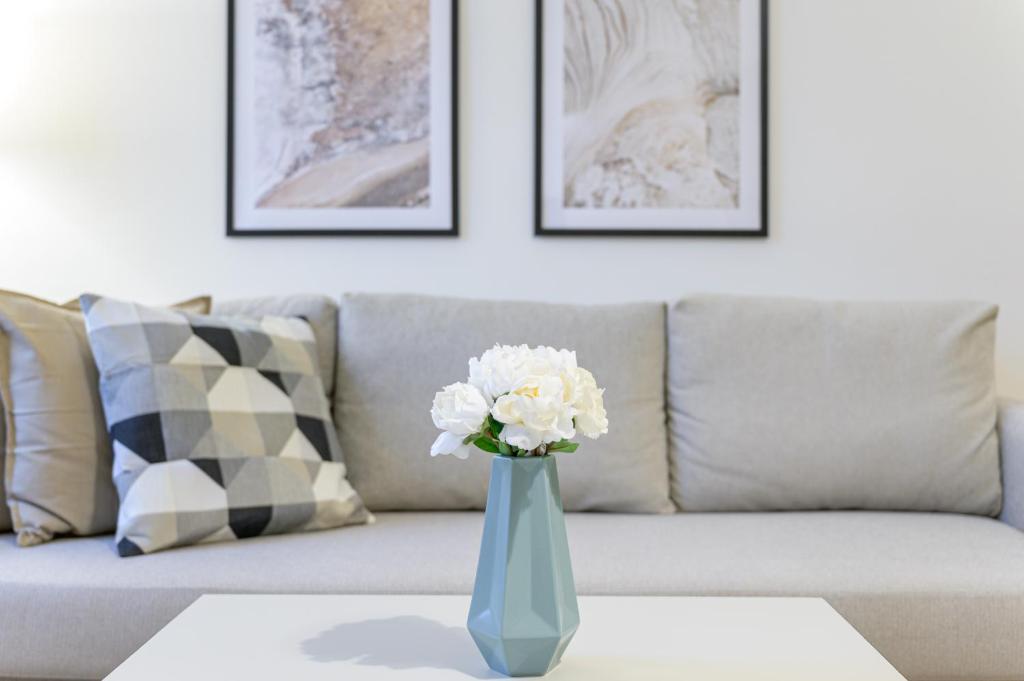 um vaso com flores brancas numa mesa em frente a um sofá em Beautiful apartment in Vienna's Heart 1c em Viena