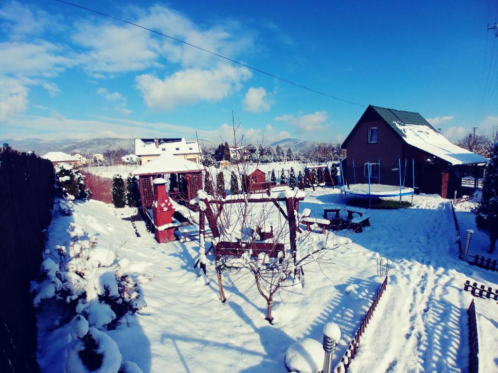 a yard covered in snow next to a house at Domek "IGOR" nad Jeziorem Żywieckim w Zarzeczu in Zarzecze