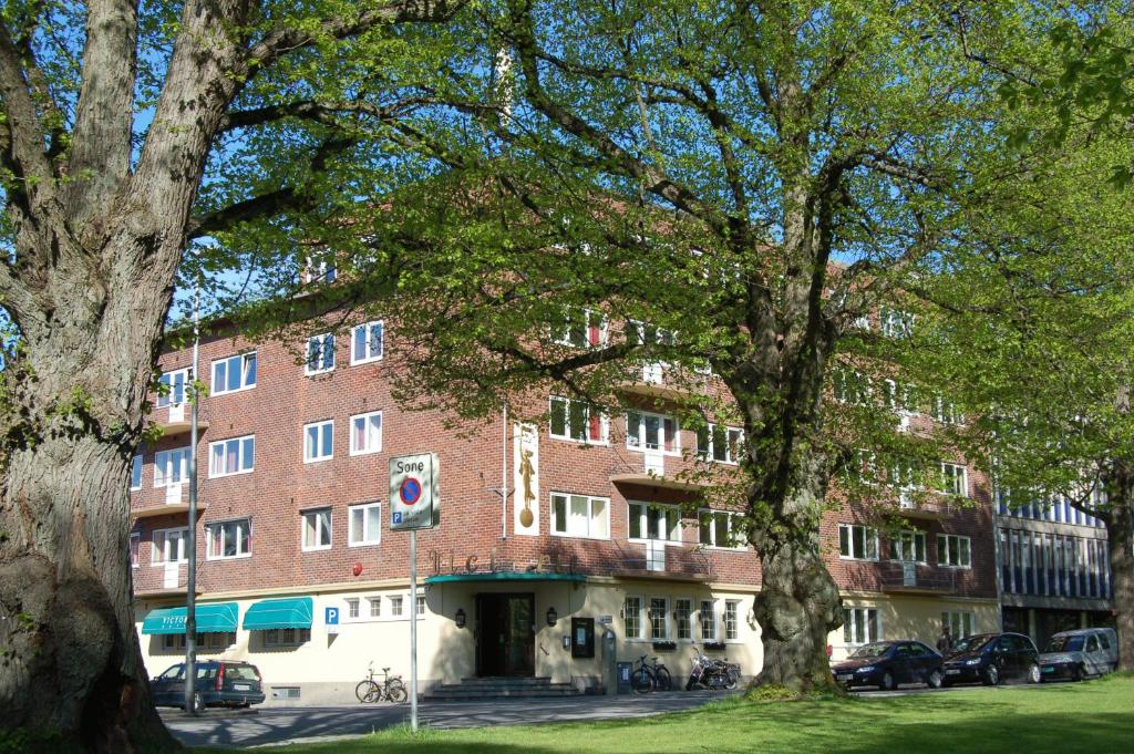 un grande edificio in mattoni con alberi di fronte di Victoria Apartments - Fredrikstad a Fredrikstad