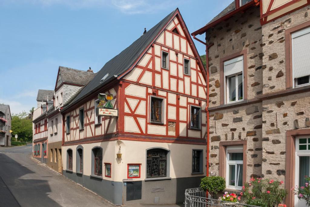 ein altes Gebäude mit roten und weißen Zierleisten in einer Straße in der Unterkunft Alte Weinstube Burg Eltz in Treis-Karden