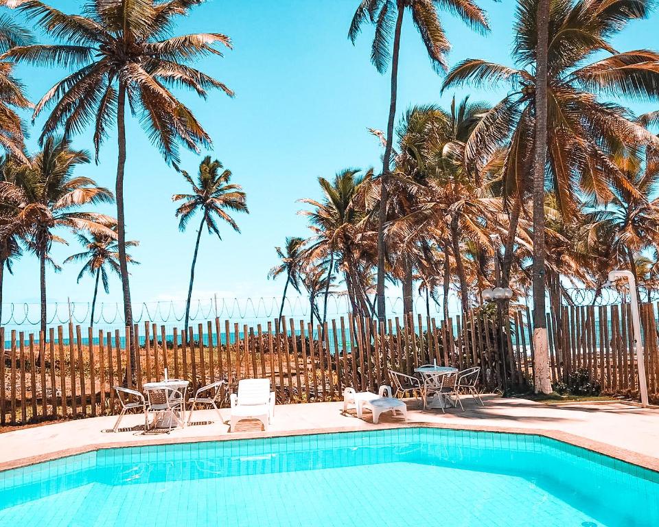 a swimming pool with palm trees and a beach at Pitaya Beach House - Charming Village By the Sea in Salvador